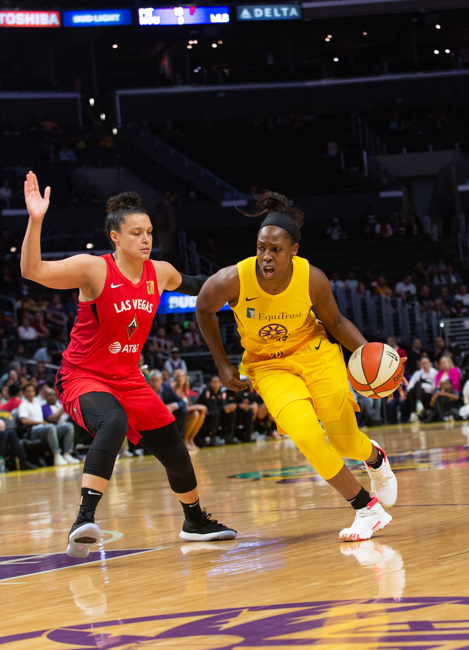 WNBA basketball game action between players in red and yellow jerseys.
