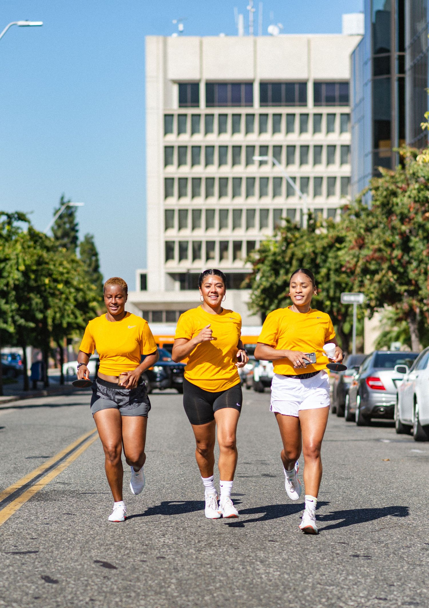 Group of athletes in yellow shirts running together on a street during training.