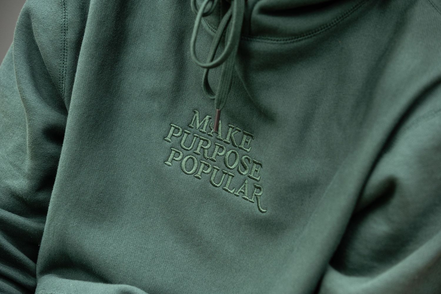 Close-up of green sweatshirt with embroidered text detail.