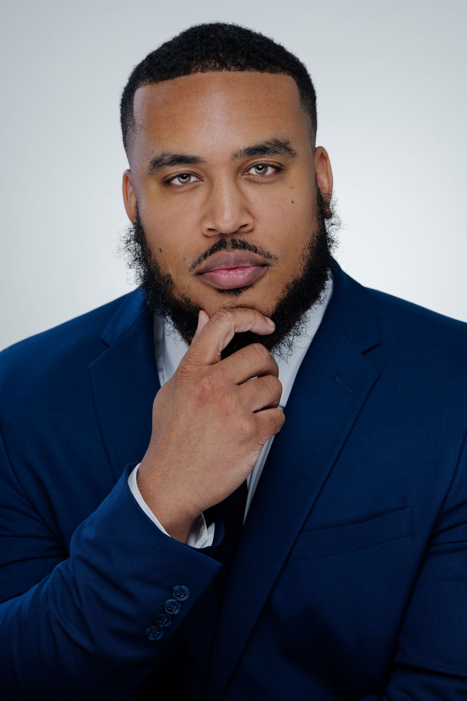 Professional headshots of a person in a navy suit against a light background.