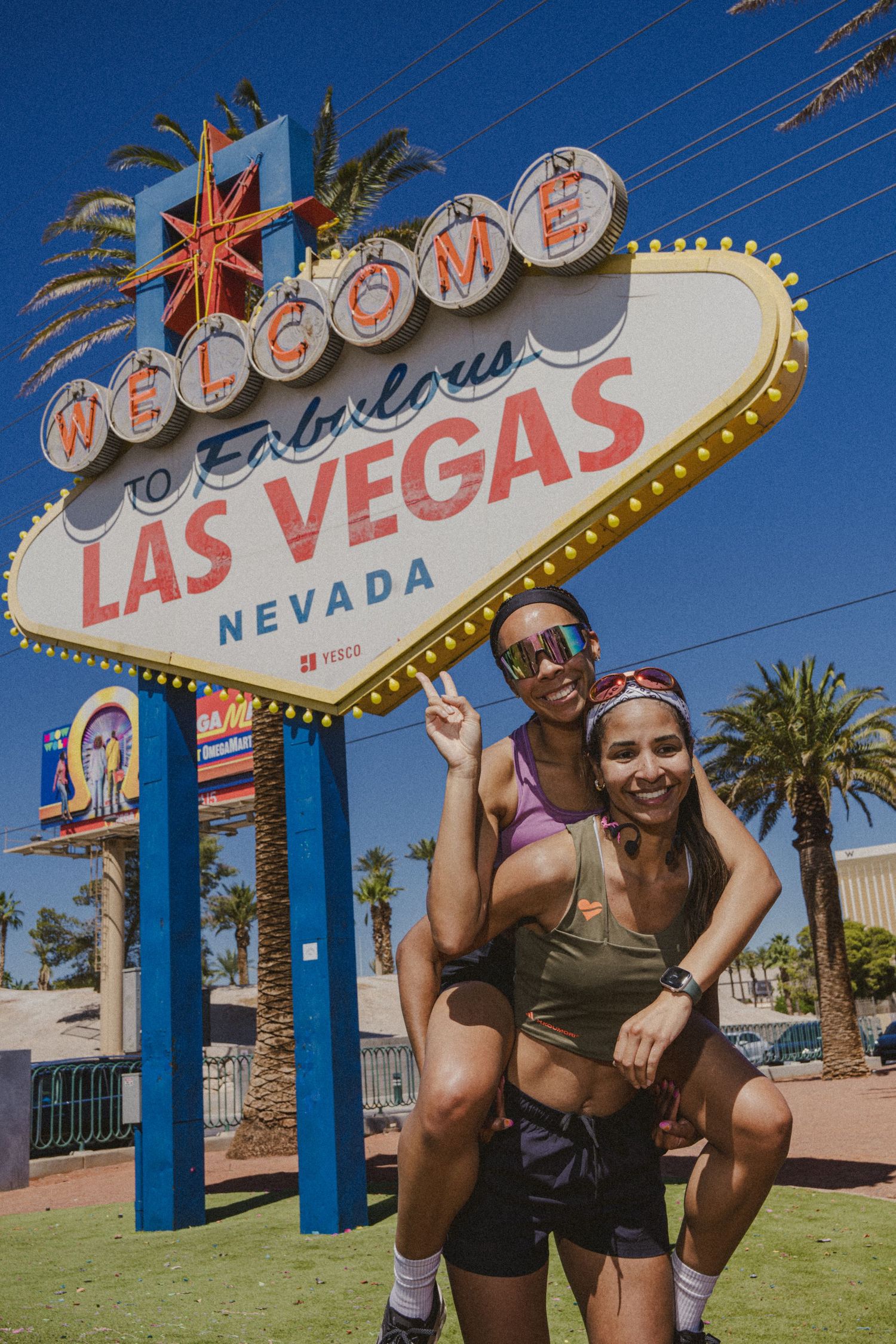 Two women pose joyfully in front of the iconic Welcome to Fabulous Las Vegas Nevada sign on a sunny day.