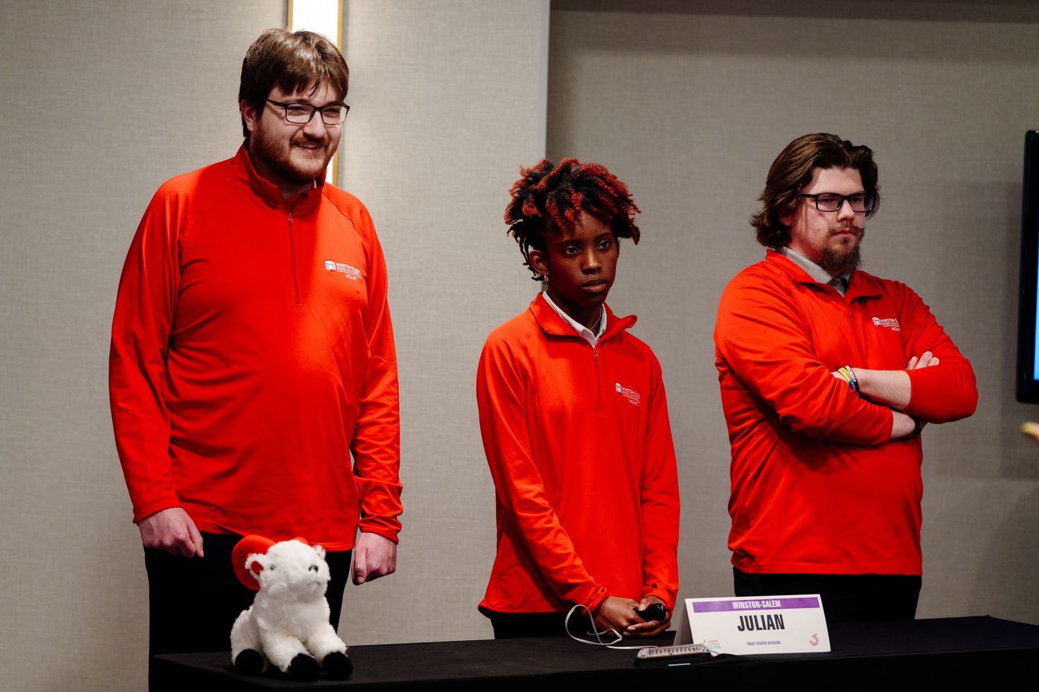 Group wearing matching red shirts seated at conference or meeting table.