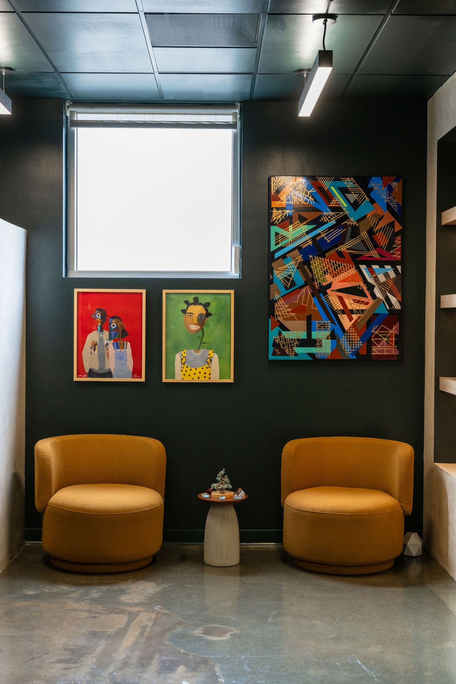 Lounge area with orange curved seating and colorful artwork on dark walls.