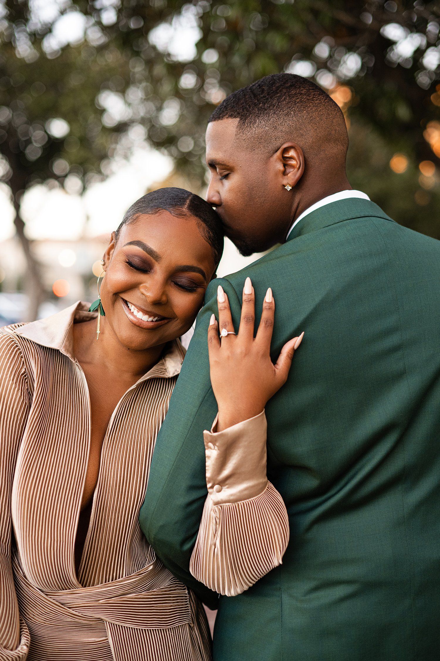 Couple in formal wear shares tender moment while showing off engagement ring.