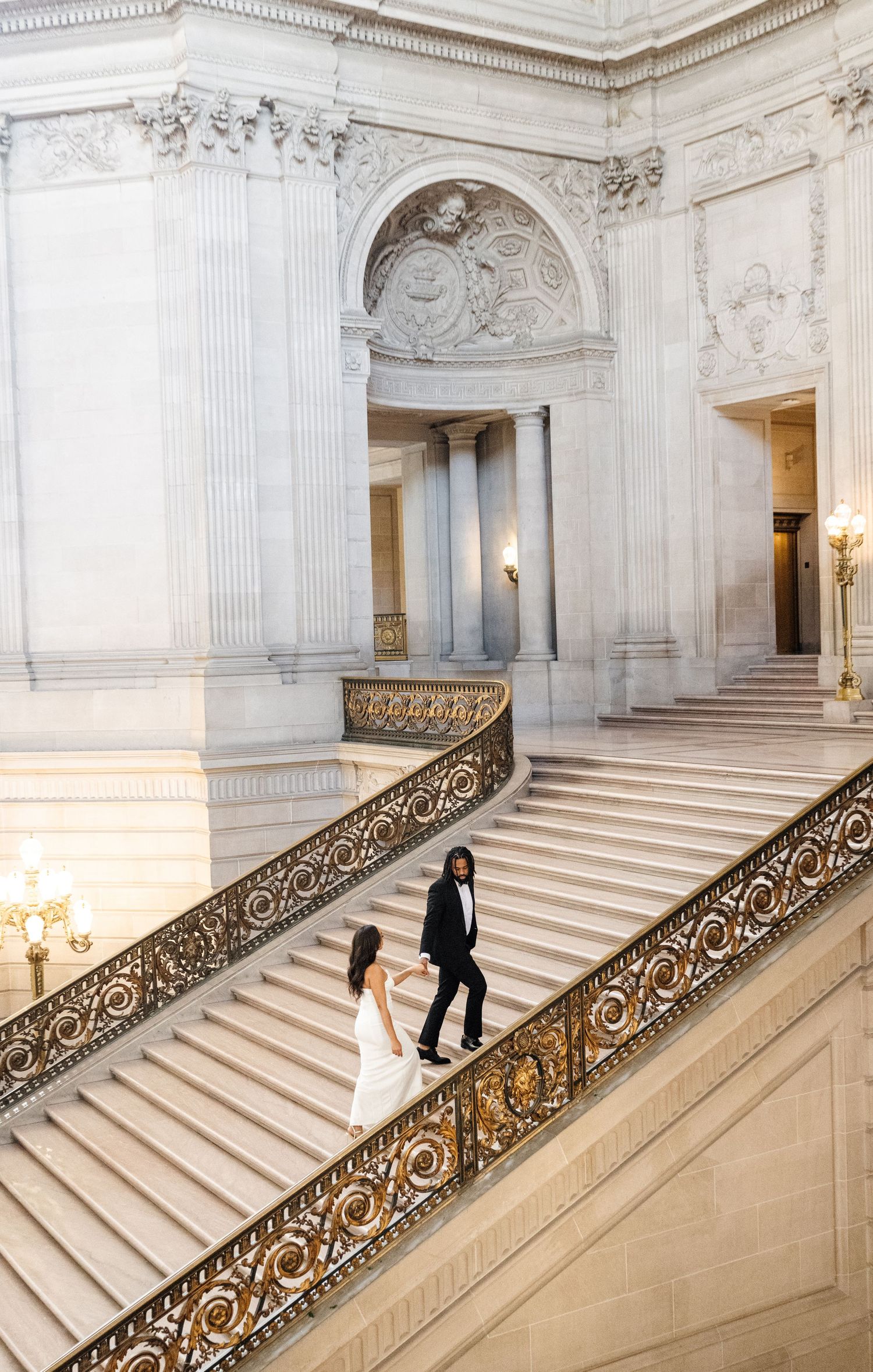 Grand marble staircase with ornate railings in an elegant white interior.