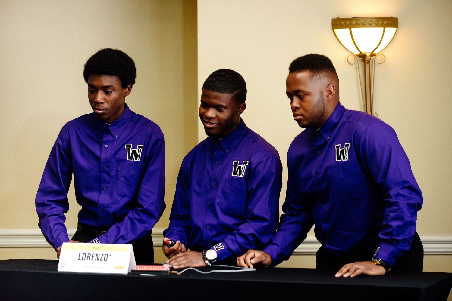 Students in purple uniforms gathered around a table during a meeting.