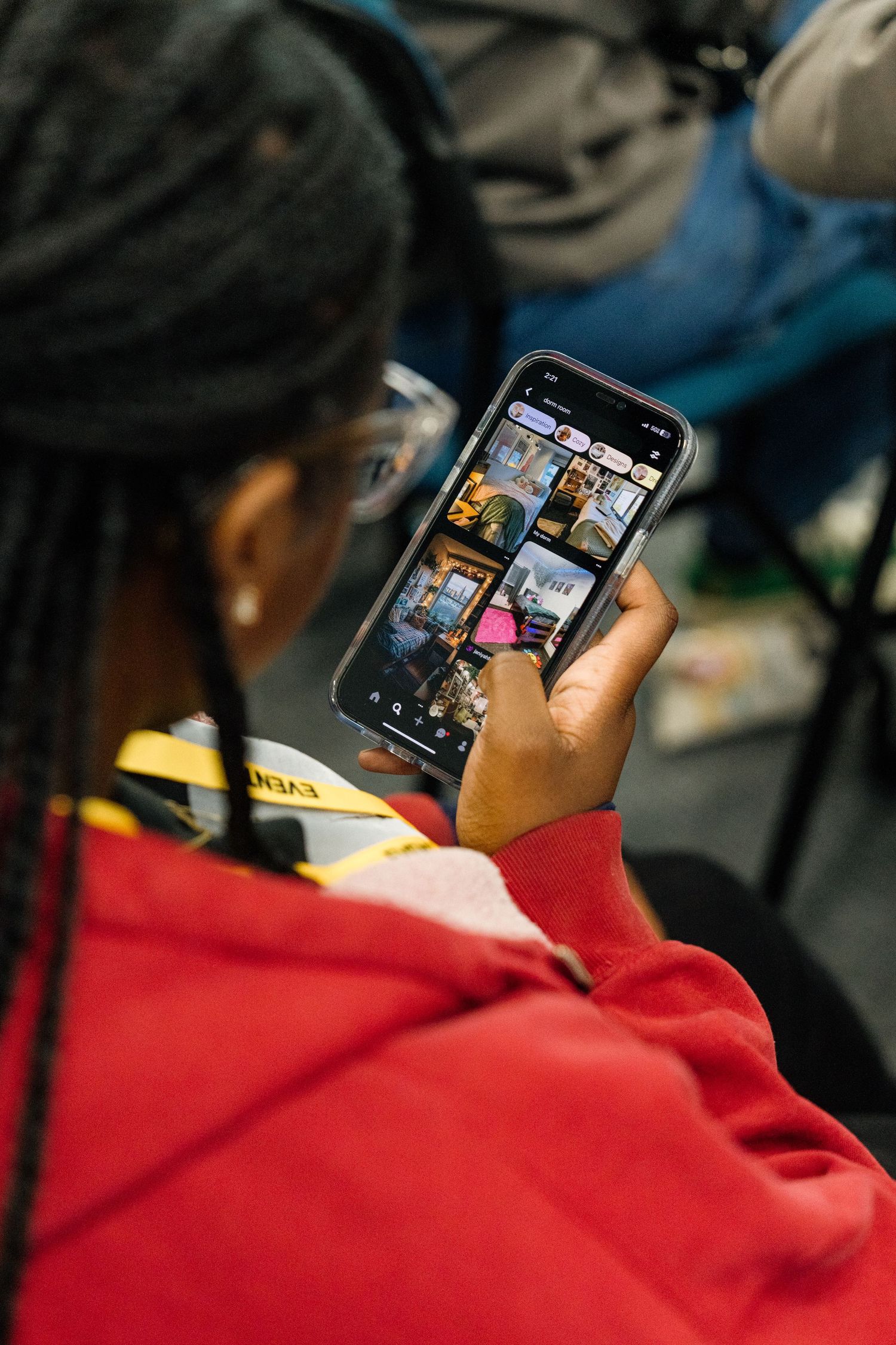 Person in red hoodie looking at photos on smartphone screen.
