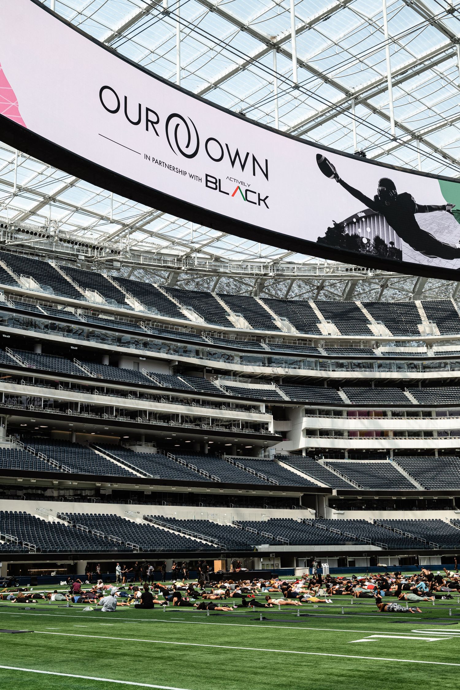 Stadium interior showing 'Our Own Black' banner and people gathered on the field below.