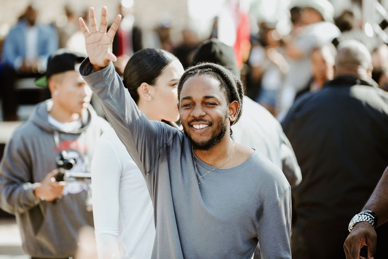 People waving and smiling at an outdoor gathering during daytime.