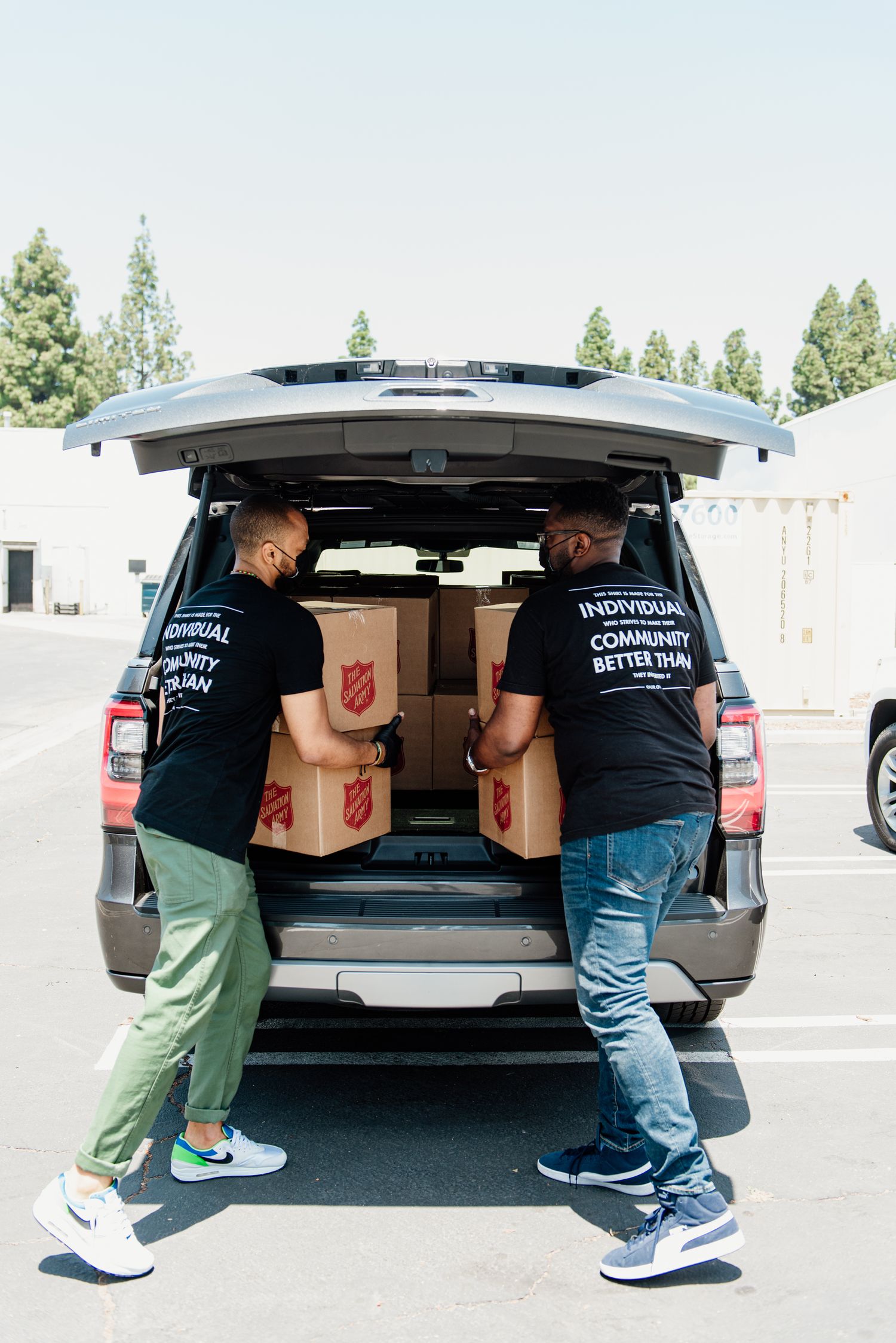 Workers in matching uniforms loading boxes into the back of a delivery vehicle.