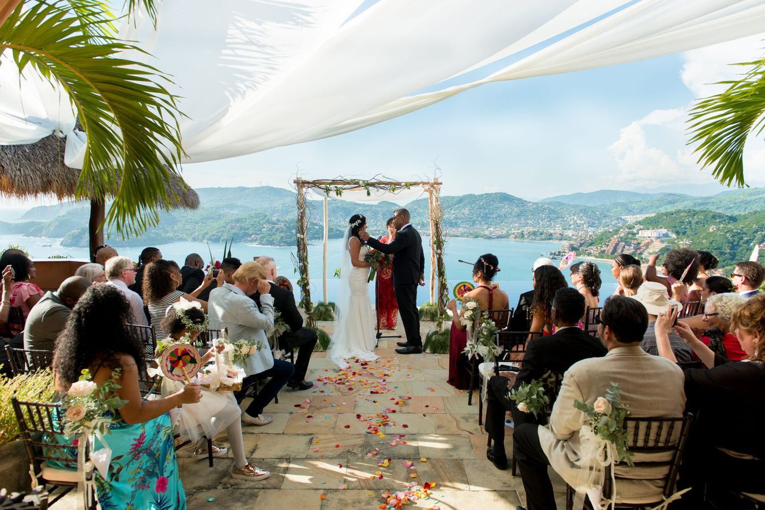 Outdoor waterfront wedding reception with palm trees and ocean views.
