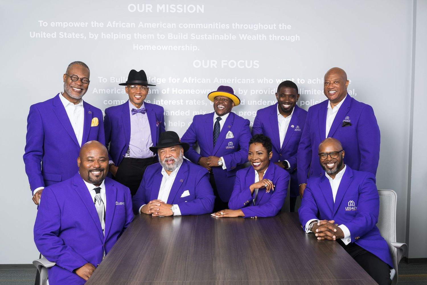 A group of men wearing matching purple blazers pose together in a formal setting.