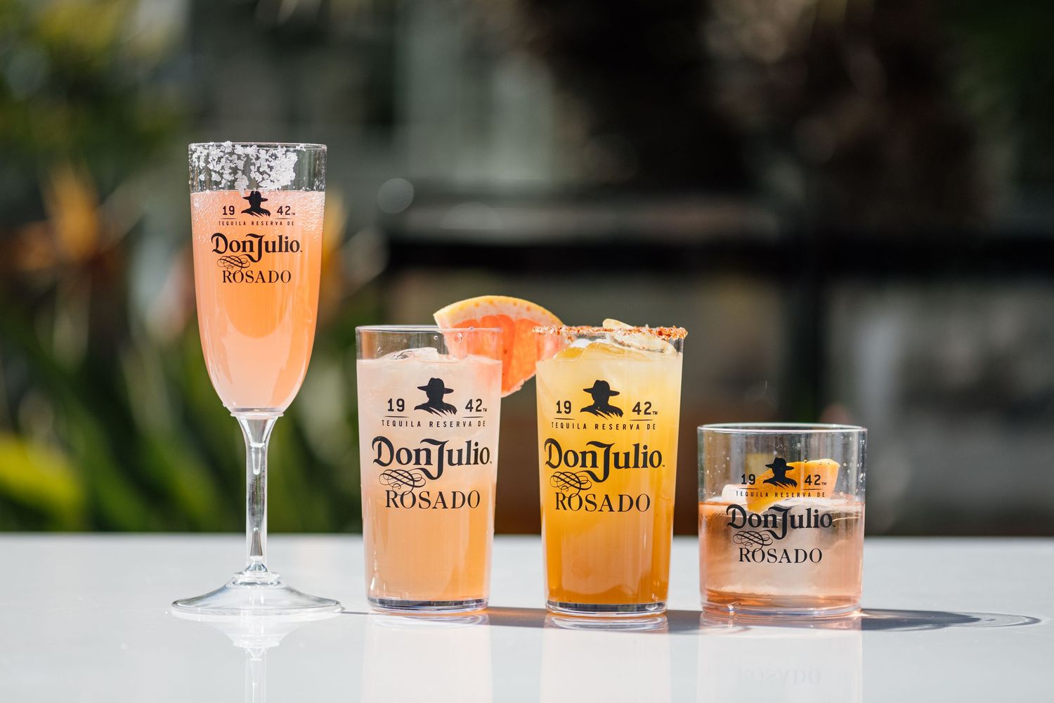 Collection of Don Julio cocktails and glasses arranged on a white surface.