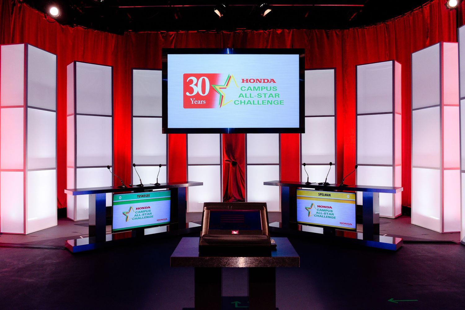 Modern stage setup with red lighting and digital display screens.