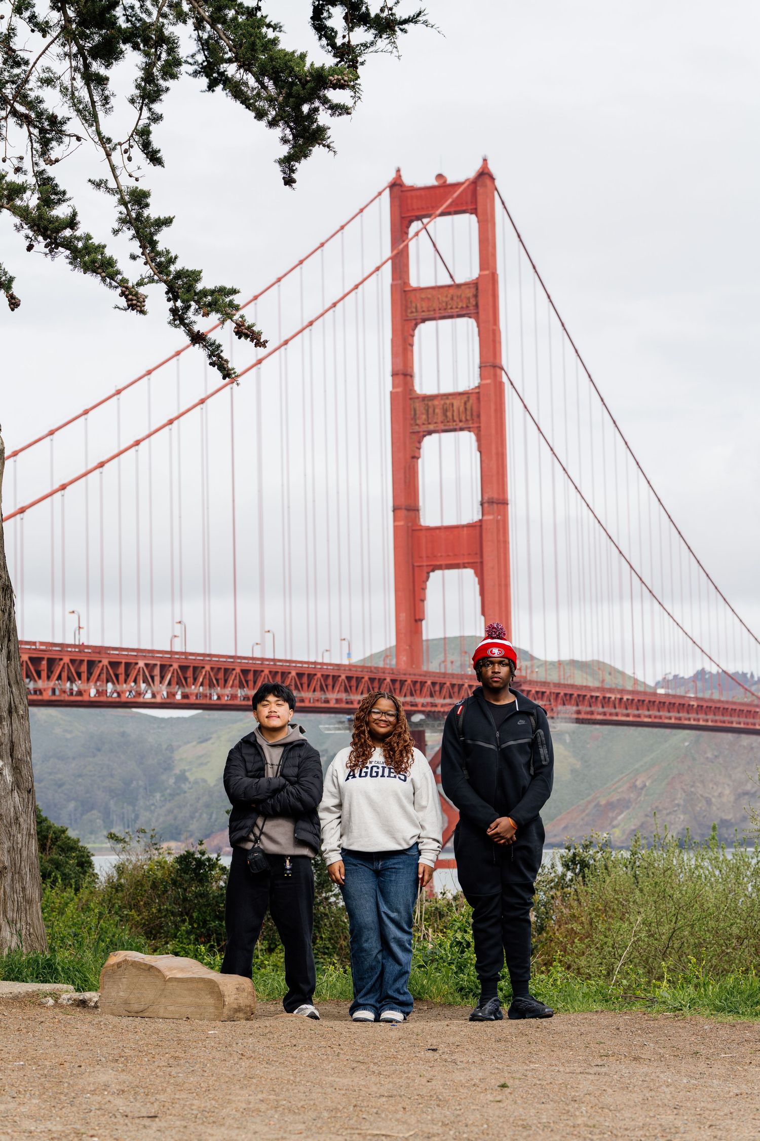 Group viewing the iconic Golden Gate Bridge from a scenic overlook on a cloudy day.