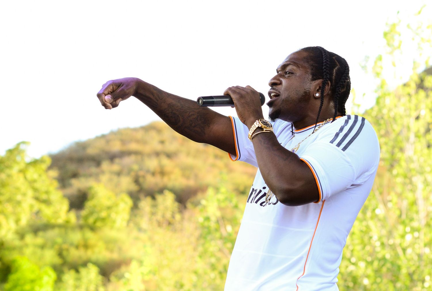 Performer in white clothing photographed against bright outdoor natural background.