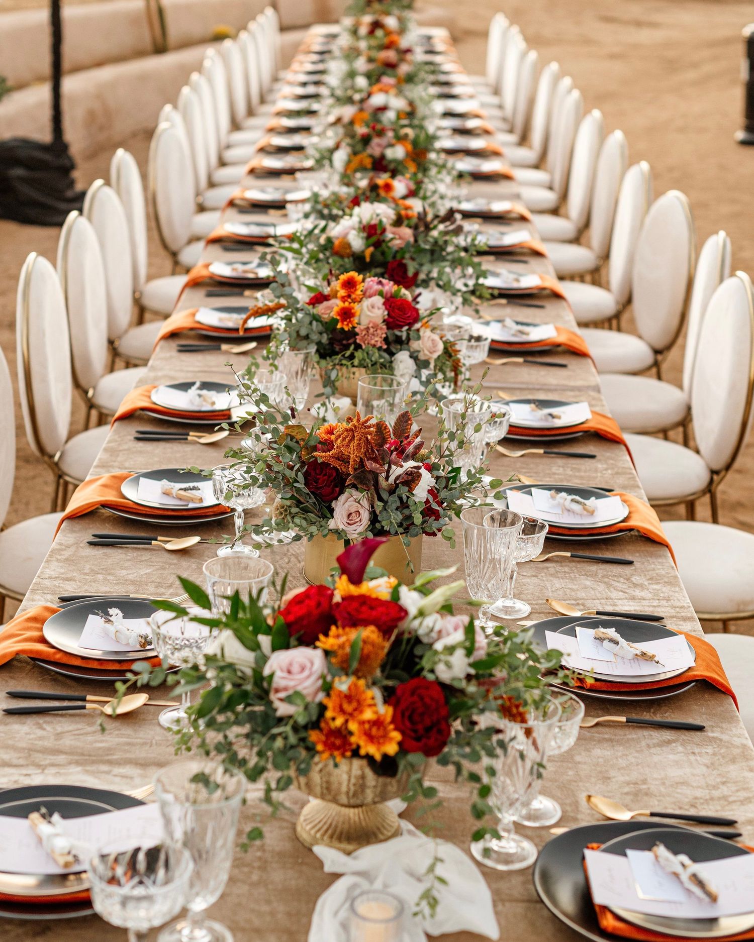 Elegant wedding table setting with colorful floral centerpieces and white chairs.