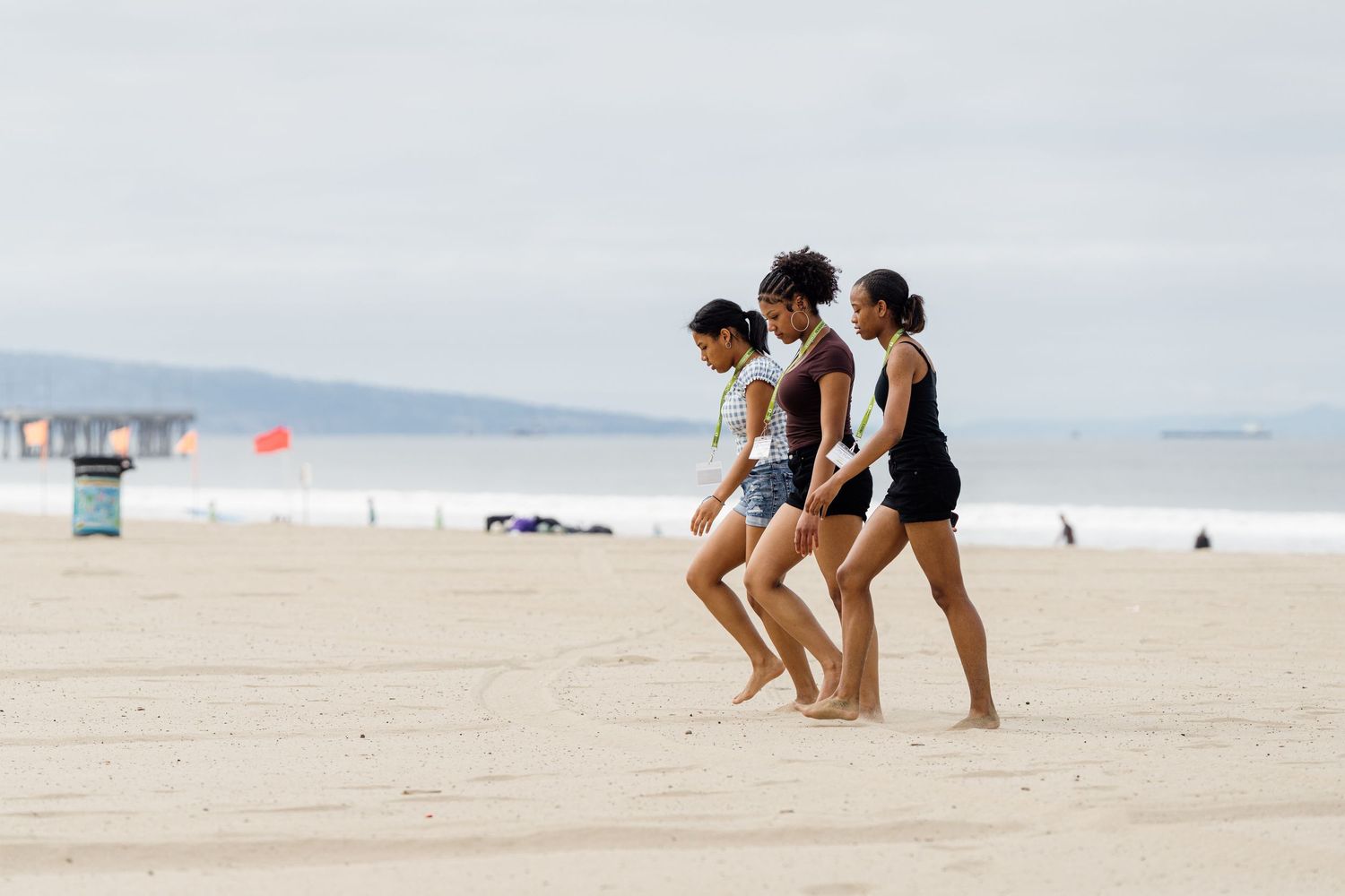 People walking and playing together on a sandy beach with ocean in background.