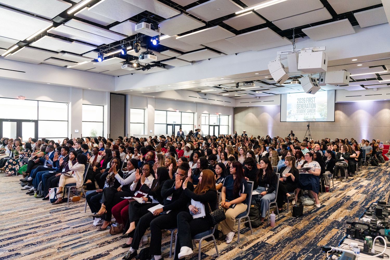 Large conference room filled with attendees seated in rows, listening to a presentation at a professional event.