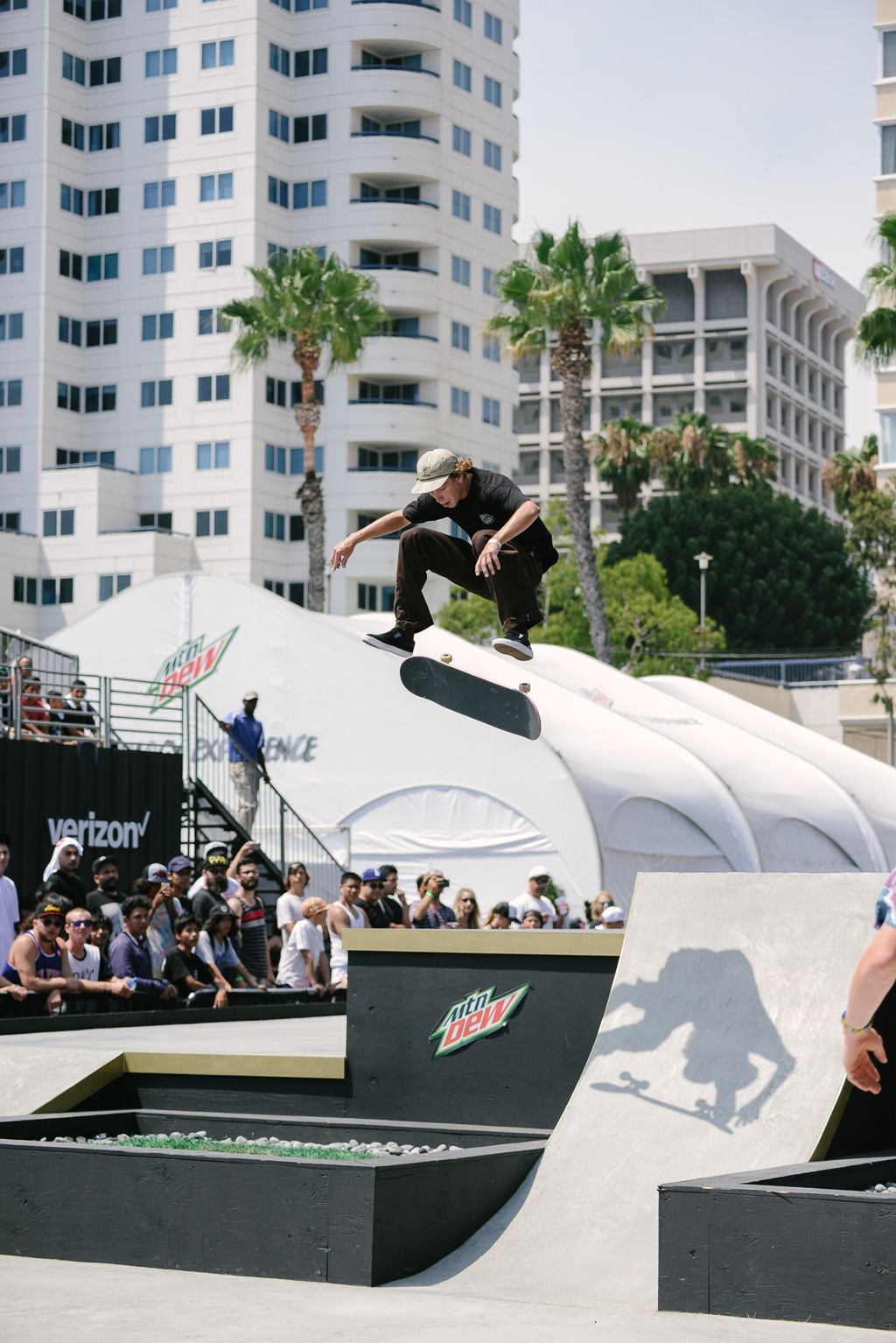 Skateboarder performing aerial tricks on a halfpipe ramp with urban buildings in background.