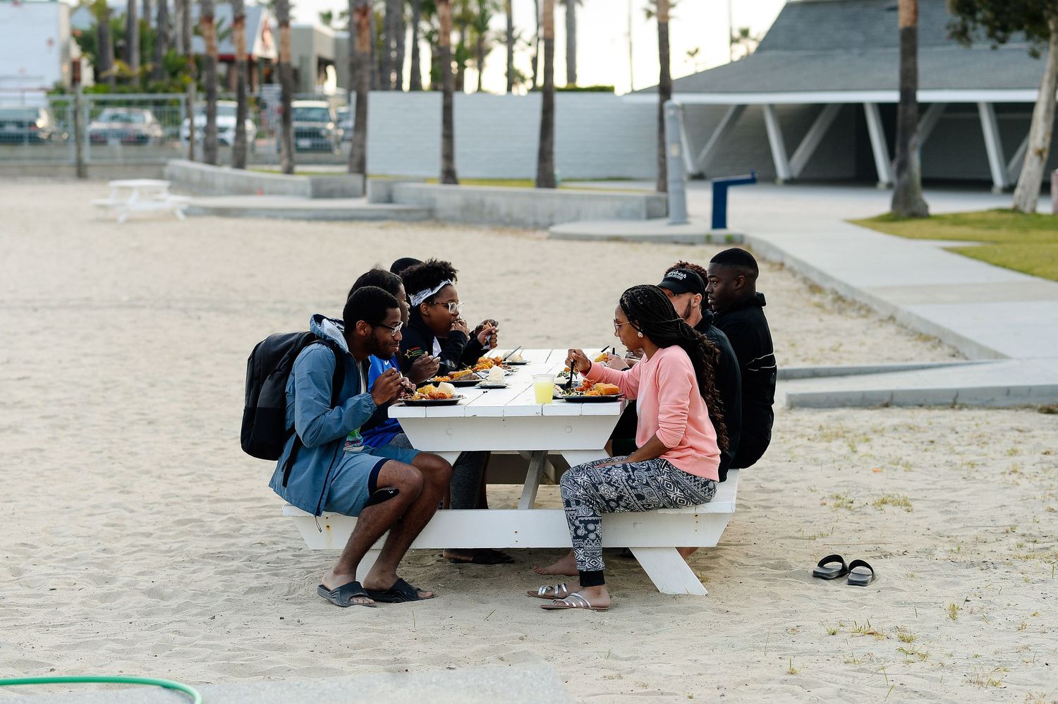 Students sitting and relaxing on concrete benches near a palm tree lined walkway.