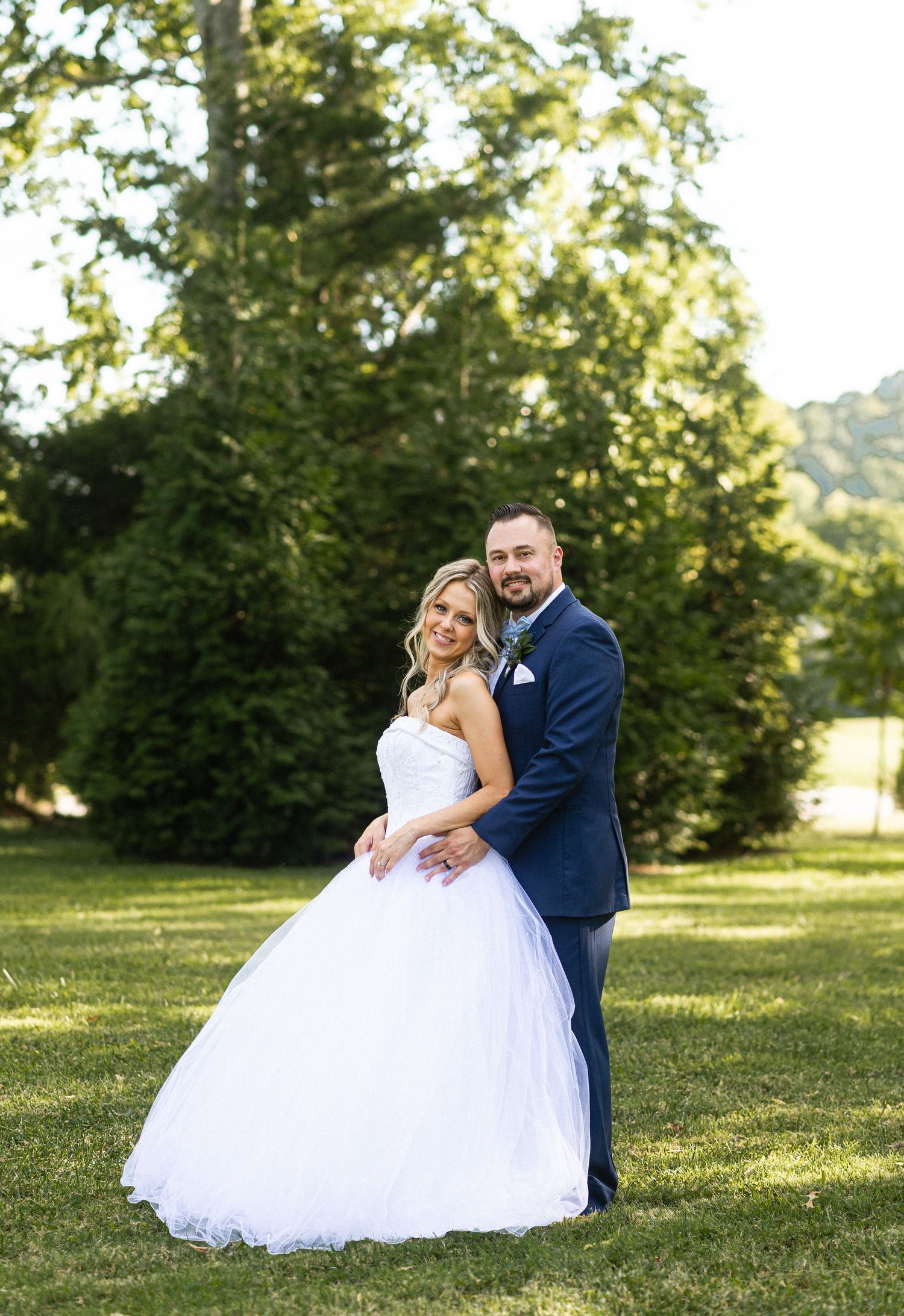 Wedding couple shares intimate moments on sunny grass lawn.