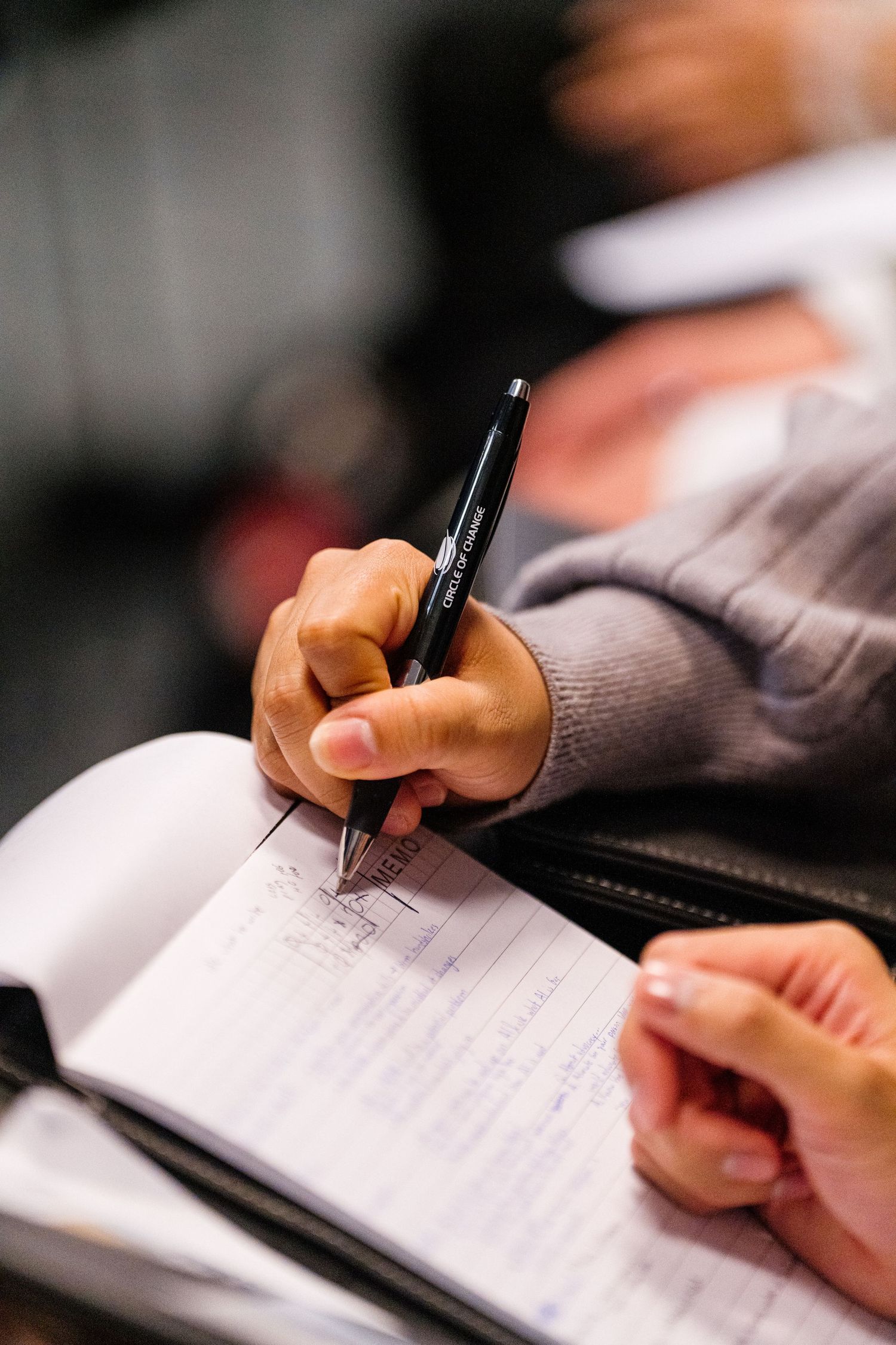 Close-up shot of hands writing on paper with a pen in a professional setting.