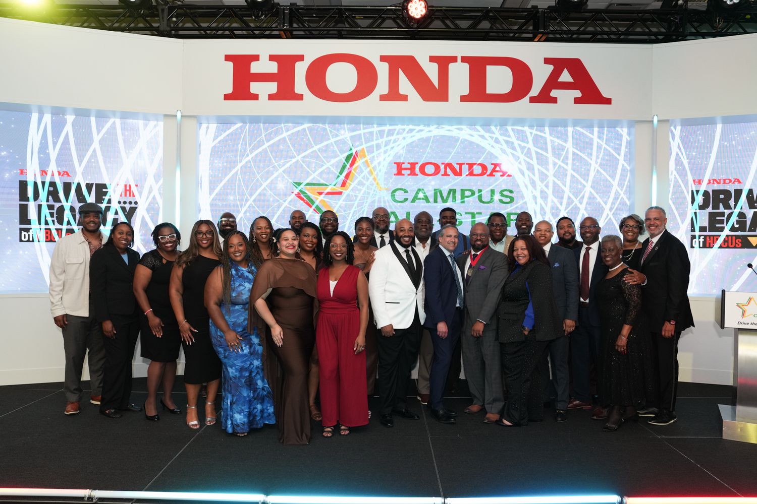 Group of professionals posing together at Honda Campus All-Star Challenge event in front of Honda branded backdrop.