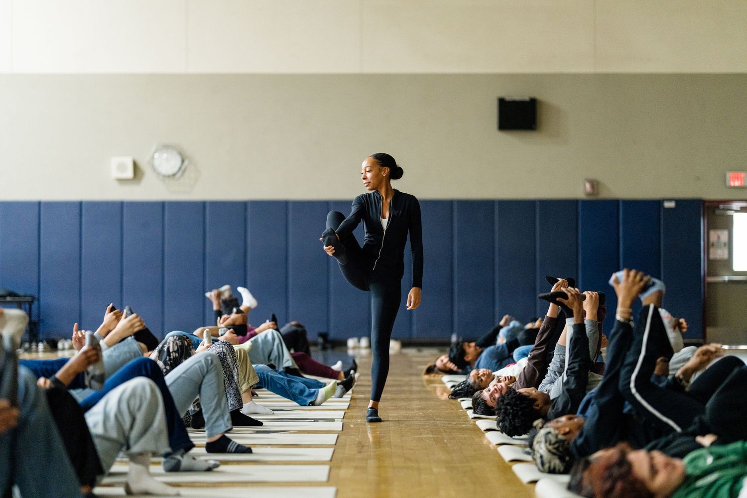 Group participating in a floor exercise inside a gymnasium with blue walls.