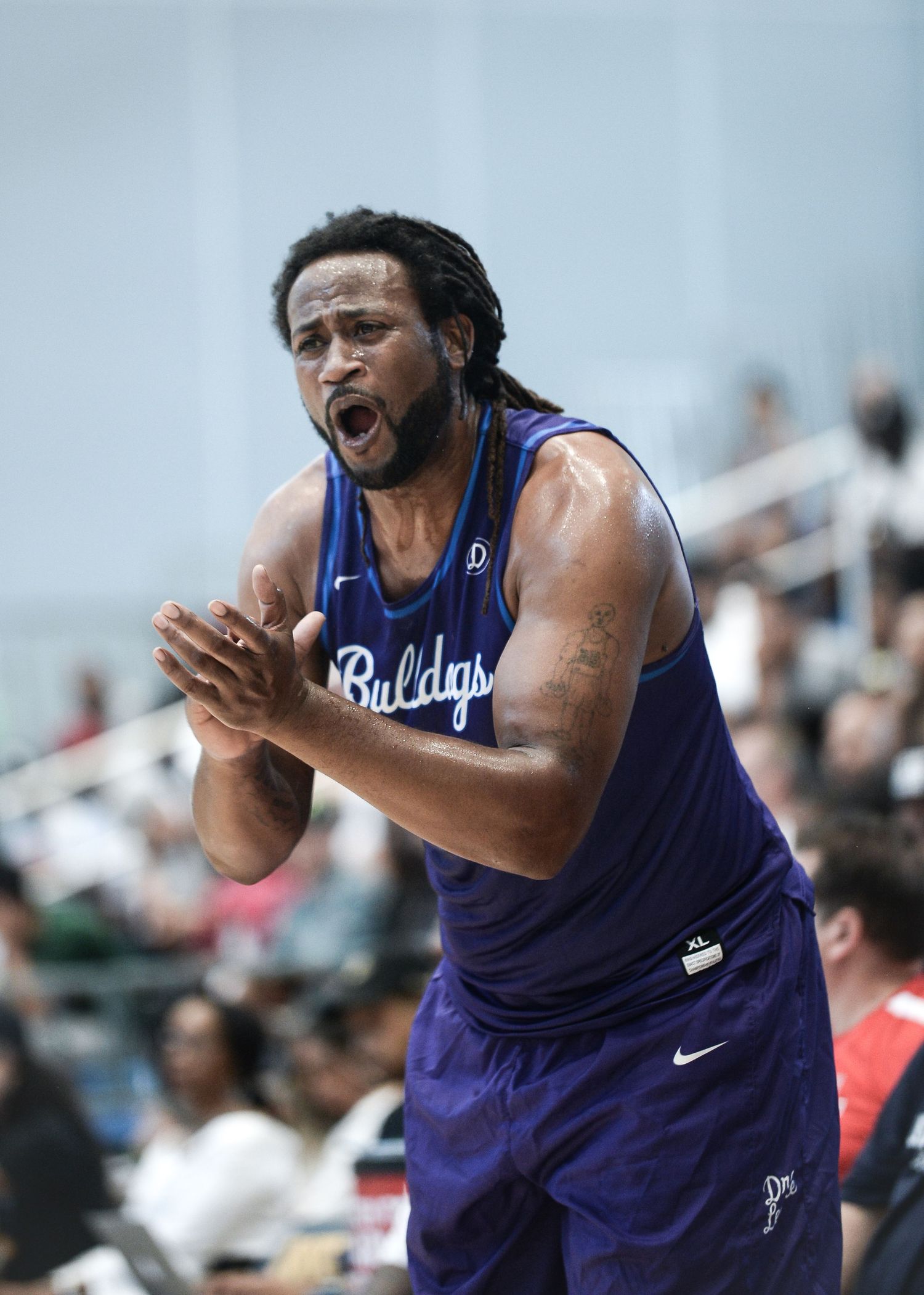 Basketball player in purple jersey shows emotion during game.
