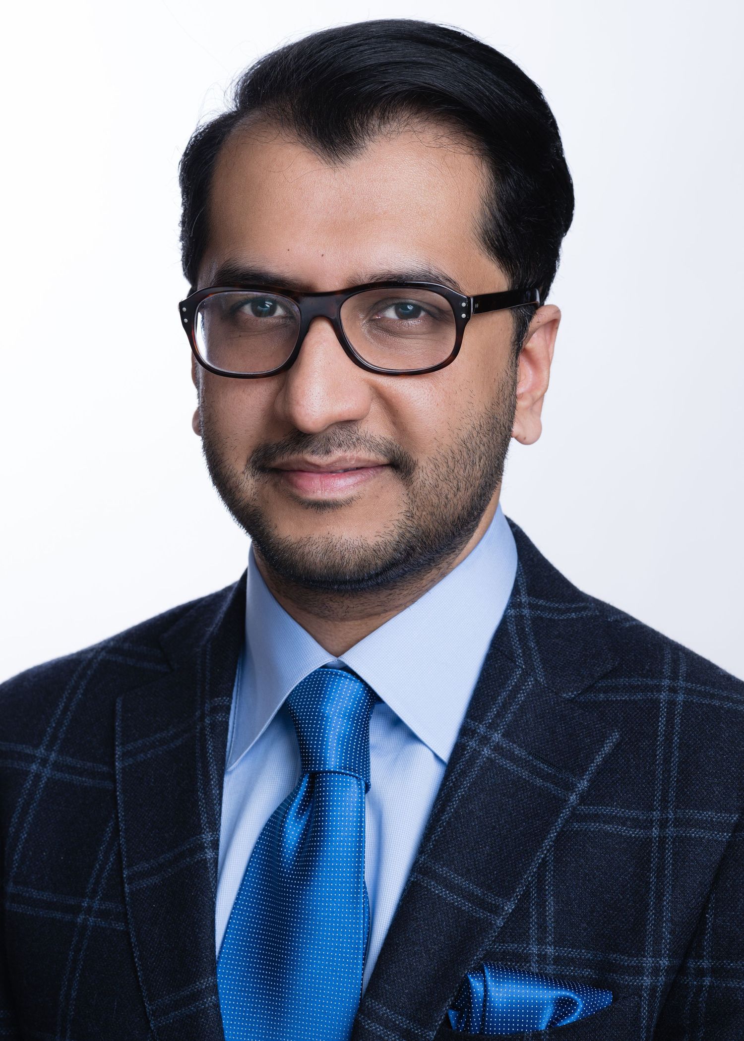 Professional headshots showing person in blue tie and checkered suit against white background.