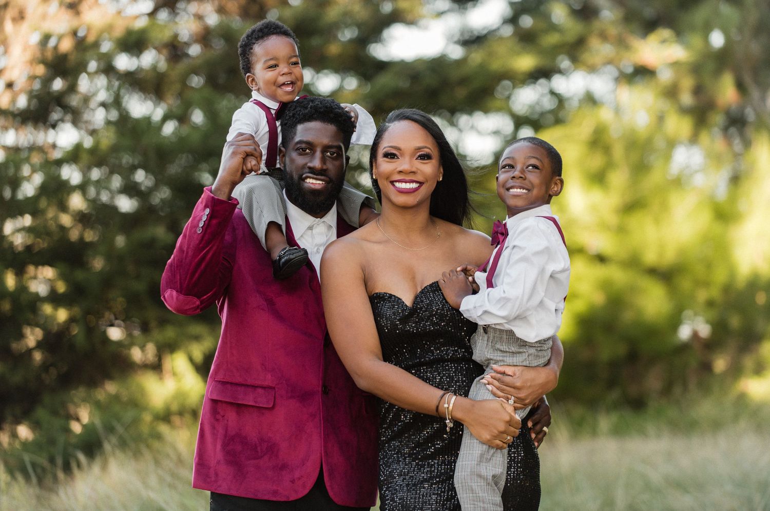 A loving family poses together outdoors in formal attire against a natural backdrop.