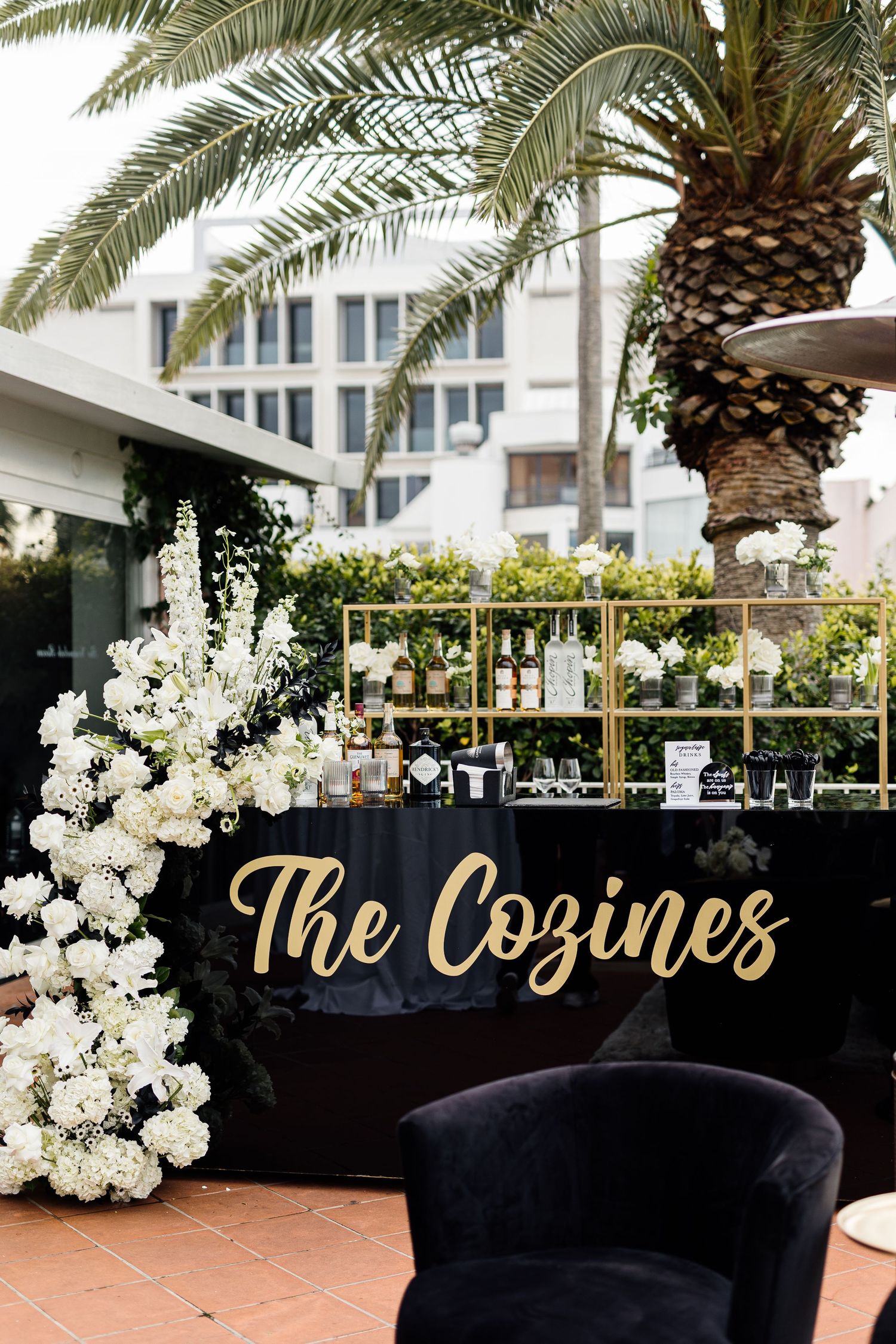 Elegant outdoor wedding bar display with white floral arrangements and gold 