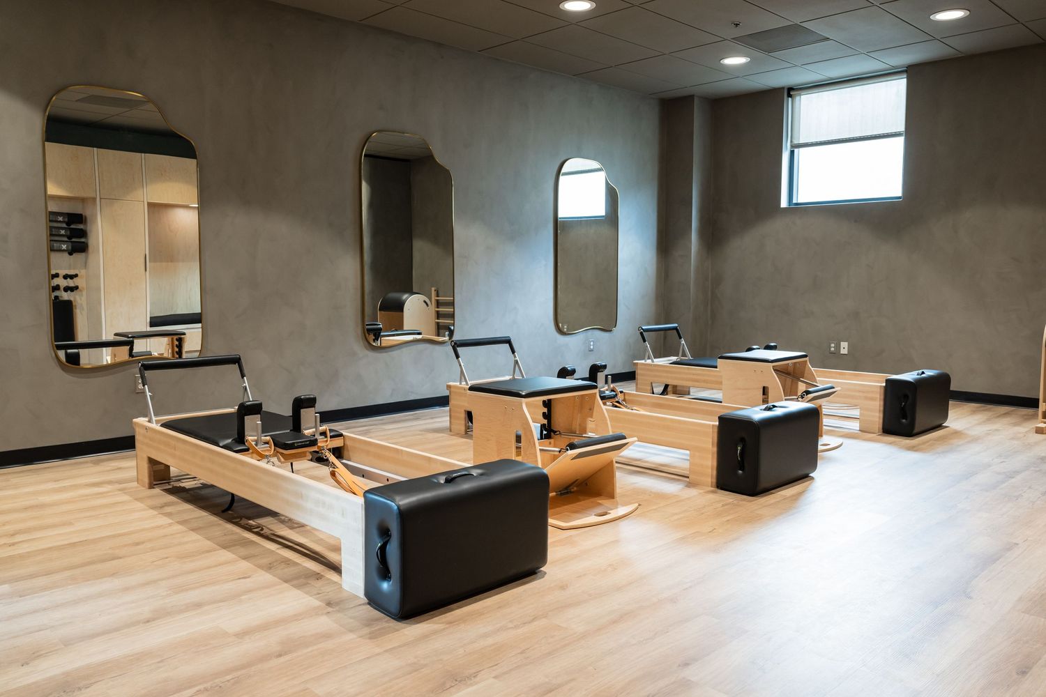 Minimalist gym space with wooden floors and black workout equipment.
