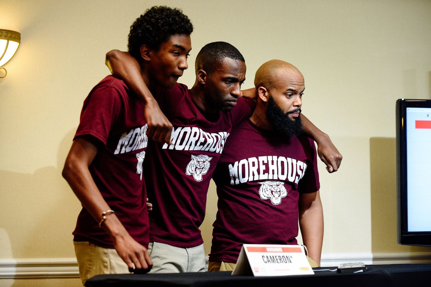 Students wearing maroon uniforms gather around a table during a meeting or study session.