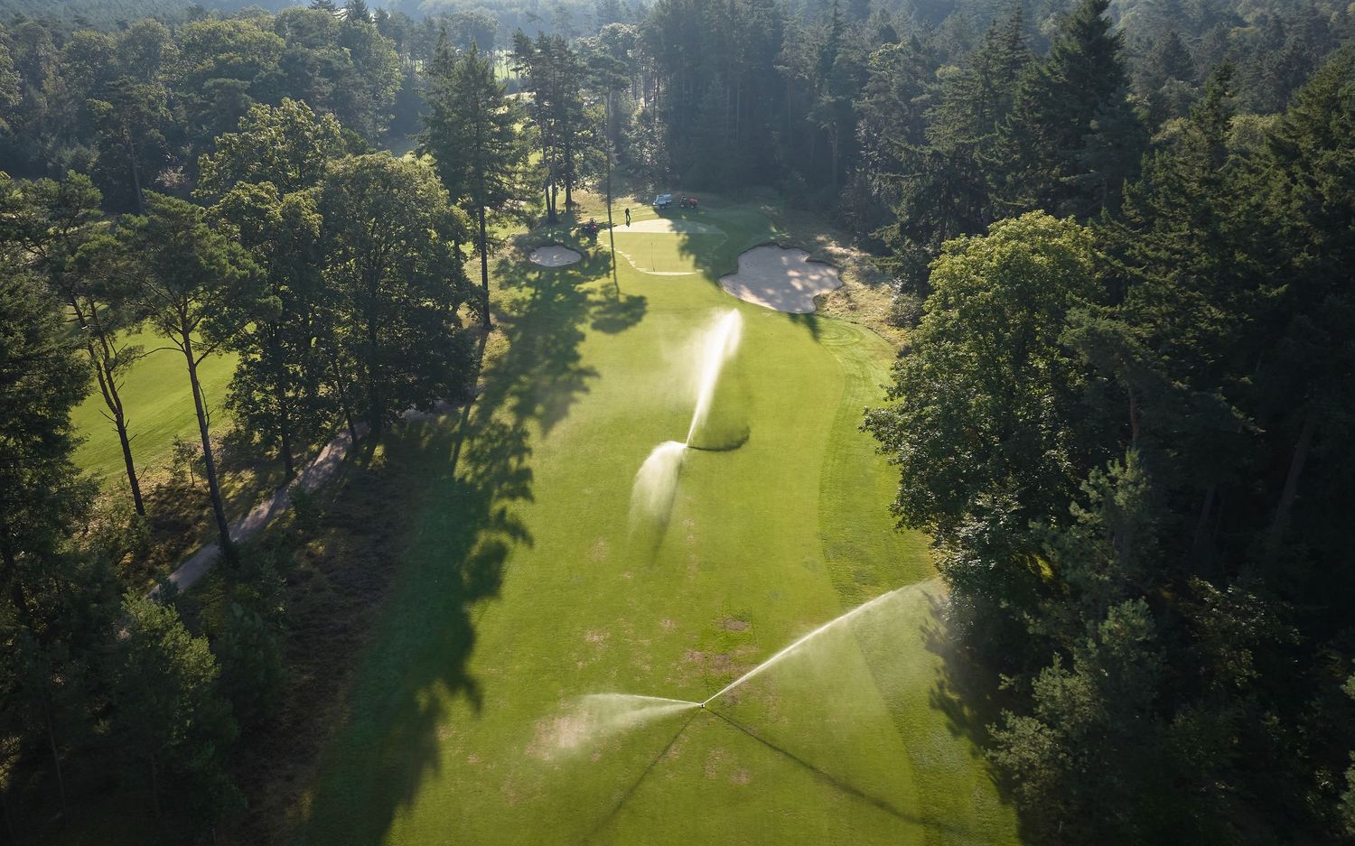 Aerial view of a lush golf course with winding cart paths and tree-lined fairways.