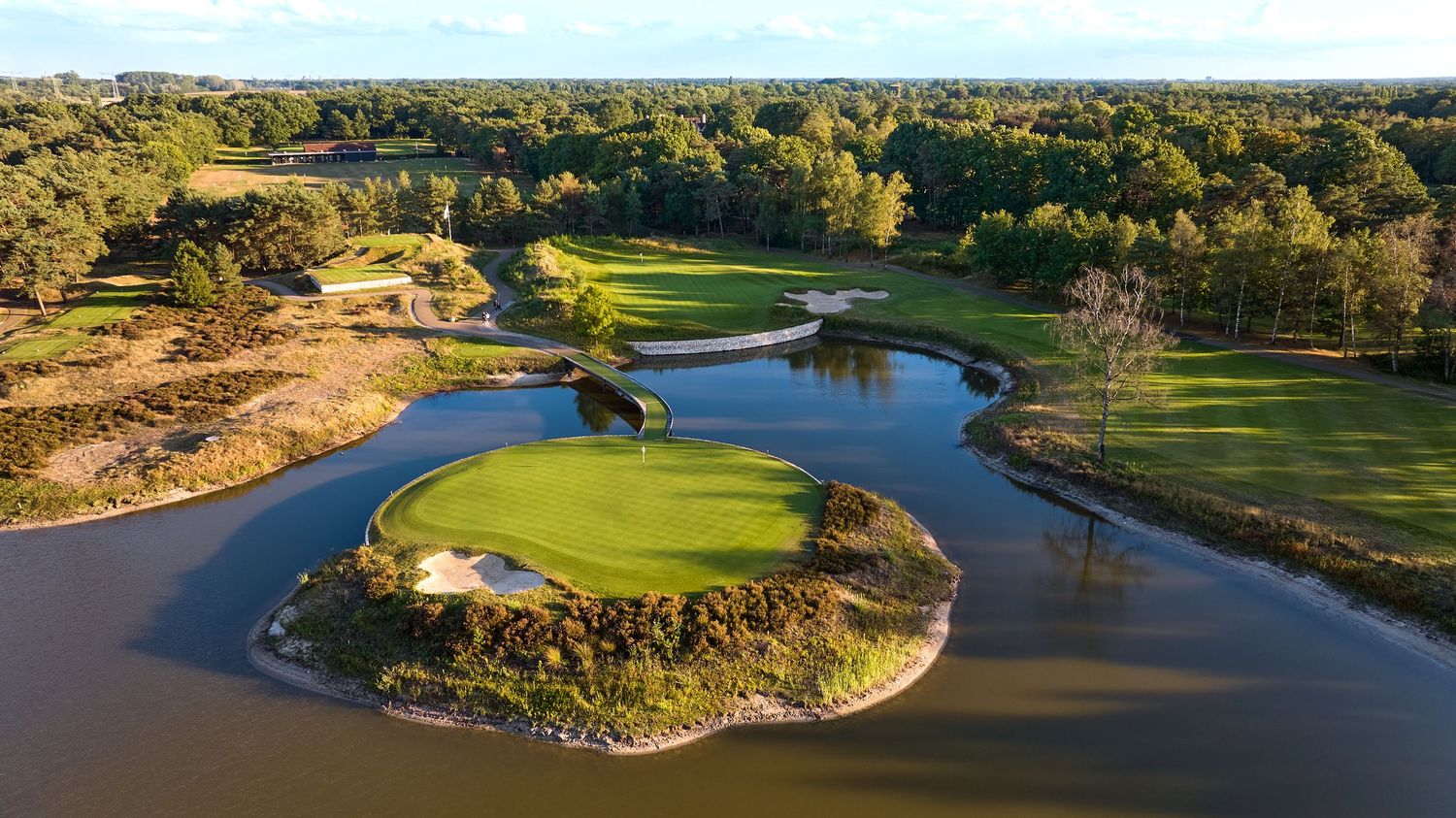 Panoramic aerial view of a scenic desert golf course with lush green fairways winding through rugged terrain and water features.