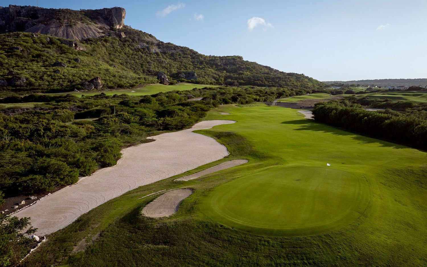 Aerial view of a seaside golf course showing multiple holes winding through rugged coastal terrain and native vegetation.