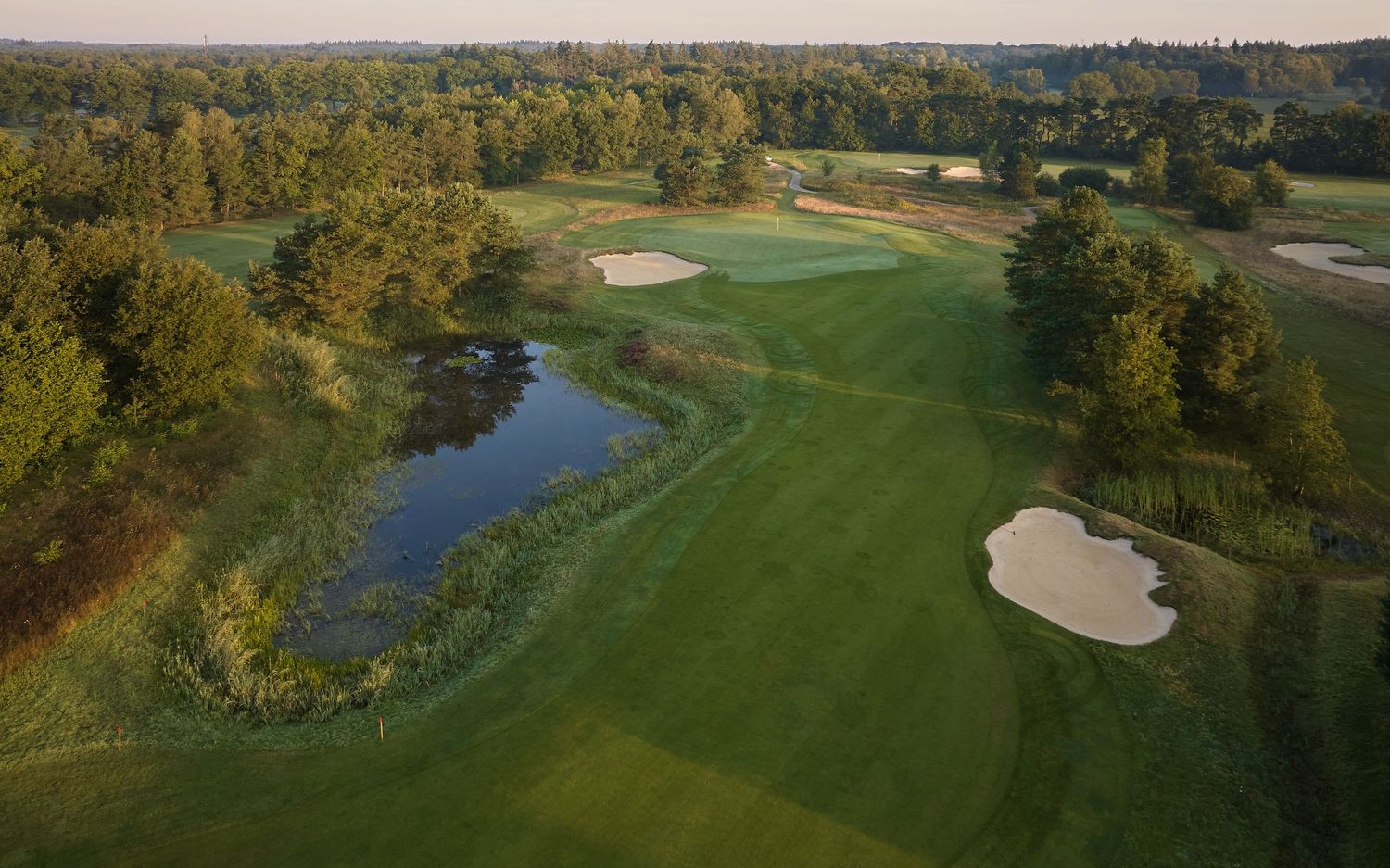 Panoramic aerial view of a golf course with water hazards and autumn foliage along the fairways.