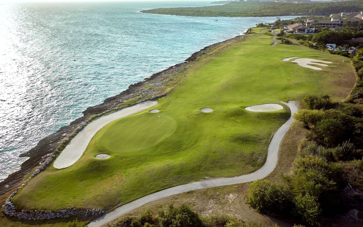 Aerial view of a coastal golf course with winding fairways and greens along the rocky ocean shoreline.