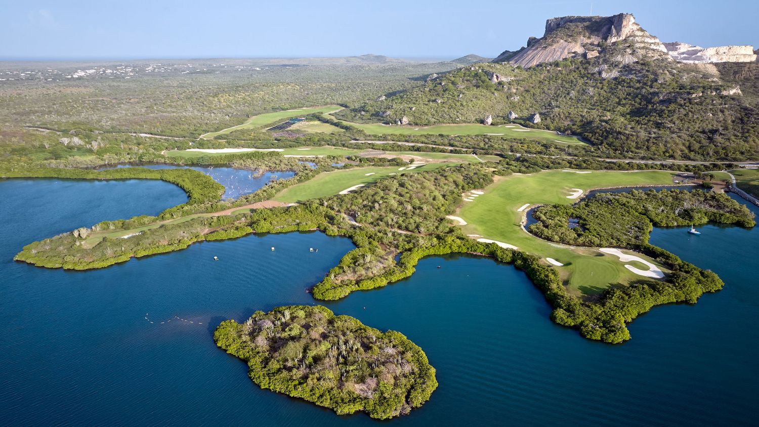 Panoramic aerial view of a coastal fortress and surrounding landscape with blue waters and green terrain.
