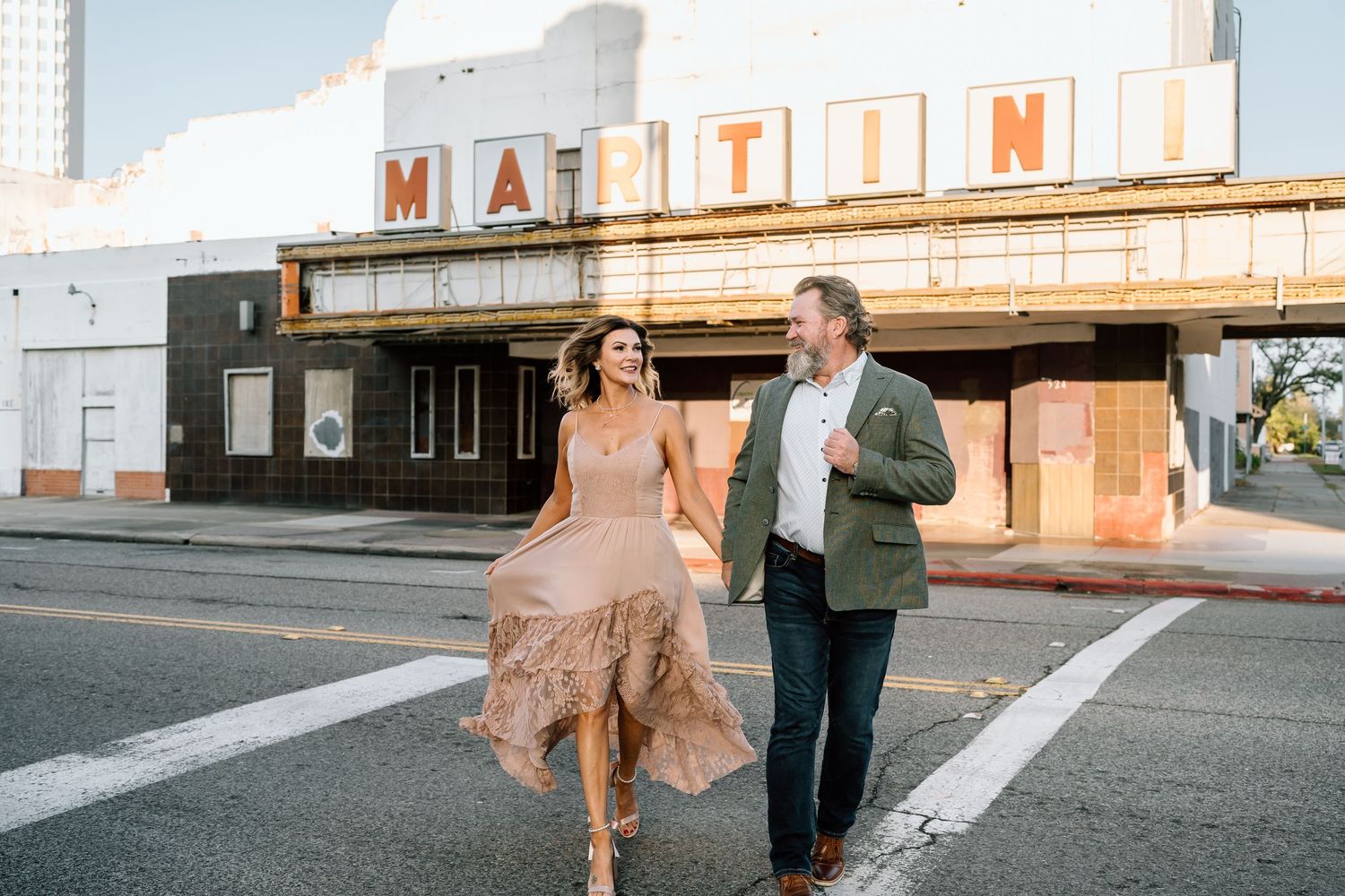 Couple in formal attire poses in front of vintage storefront at sunset.