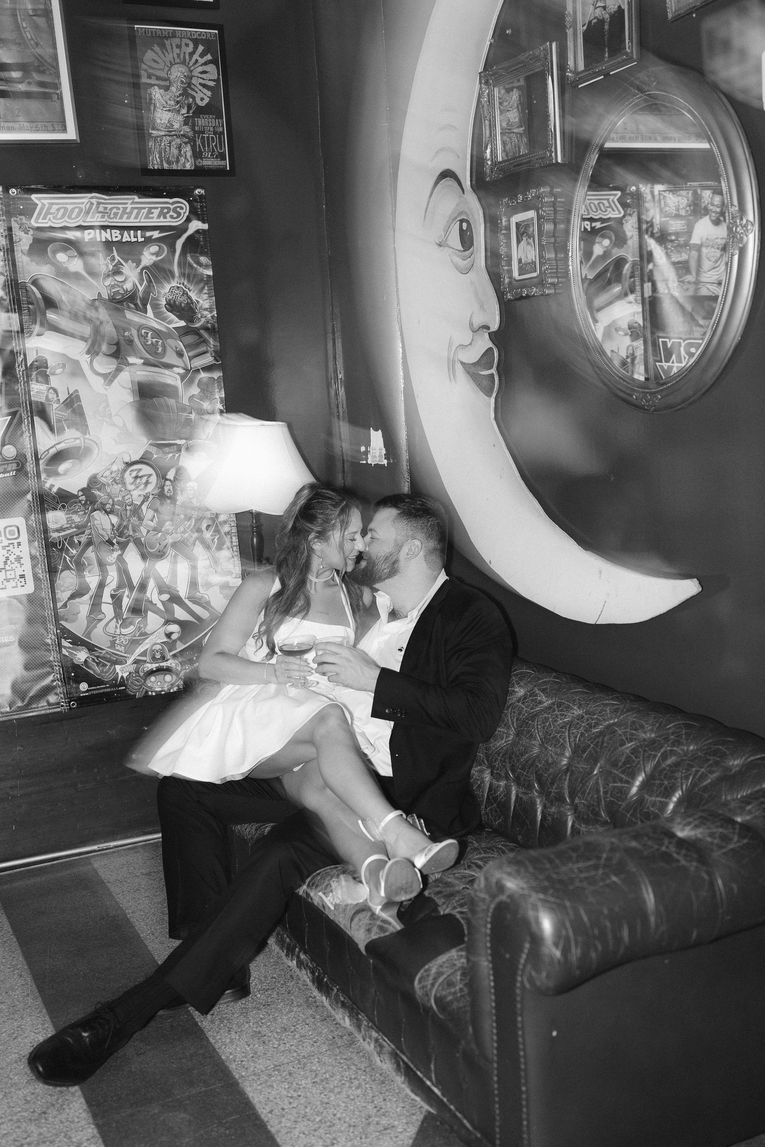 Artistic black and white sequence of romantic moments on a leather couch with wall decor.
