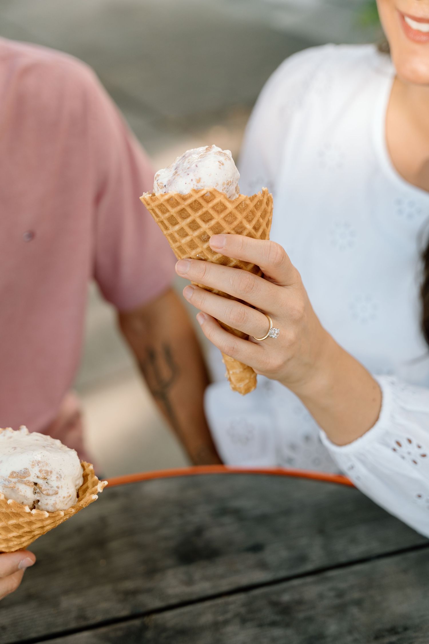 Close-up sequence of hands holding and eating ice cream sandwiches on a rustic wooden table.