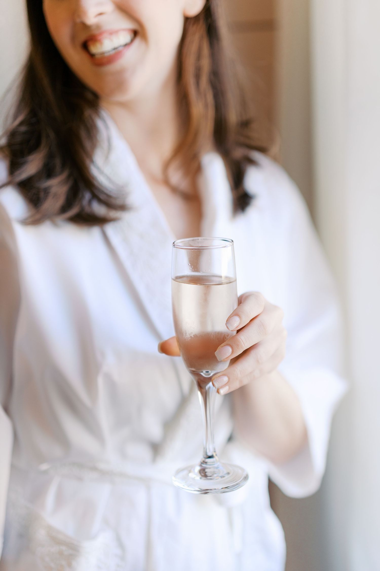 Champagne glasses held in celebration during wedding preparations.