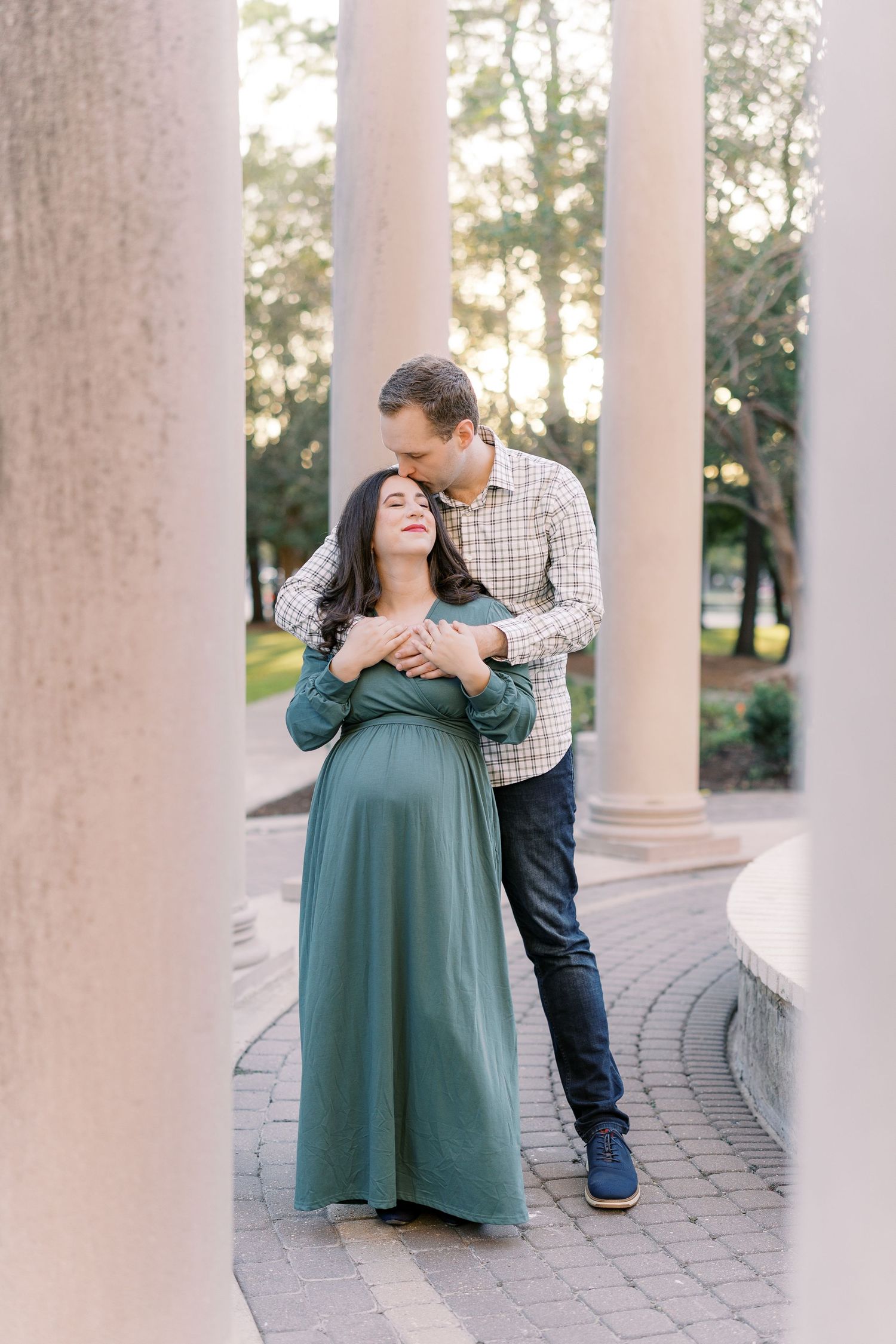 A romantic moment captured between a couple near white columns at sunset.