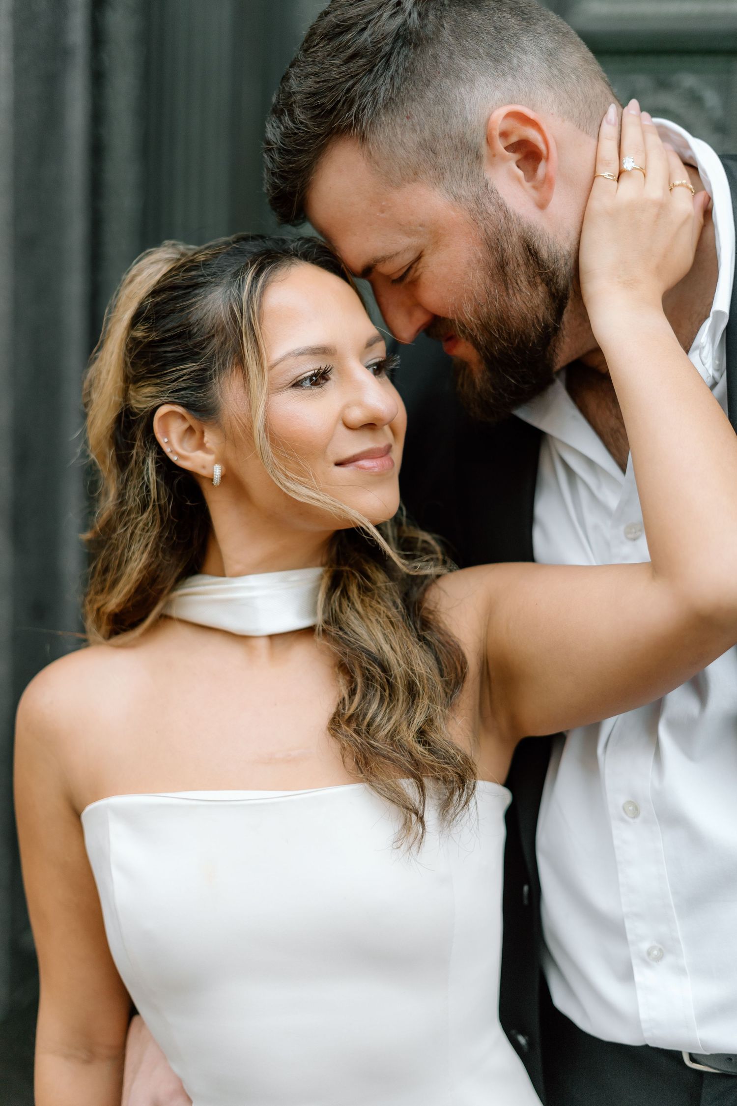 Romantic couple in formal attire sharing an intimate moment against a dark background.