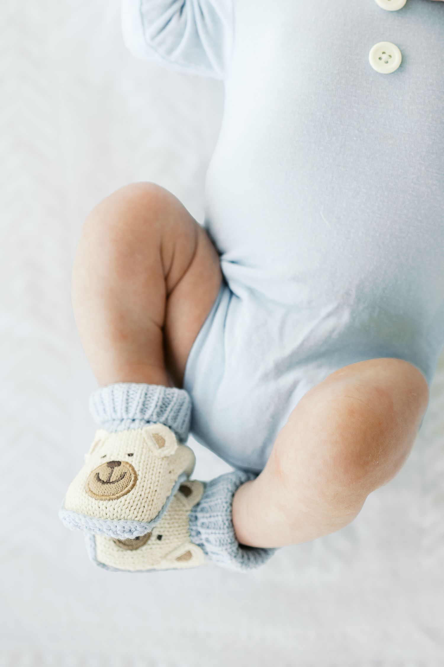 Close-up of tiny baby feet wearing knitted booties with smiley face design.