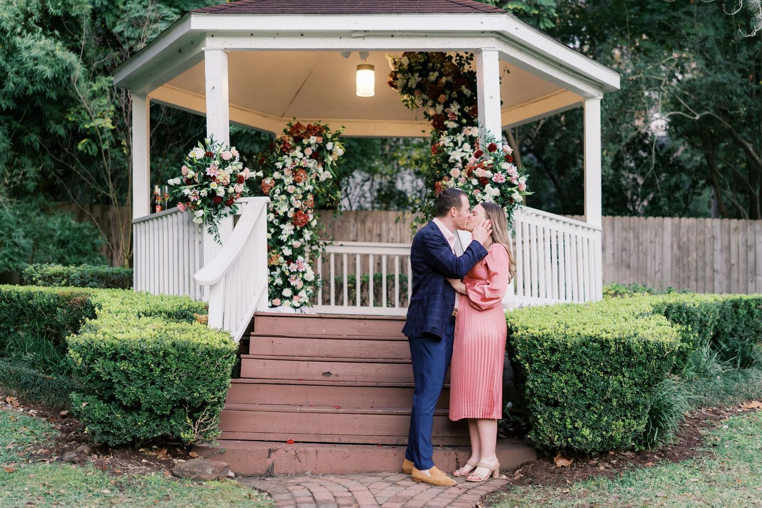Couple shares romantic moments on a porch decorated with floral arrangements.
