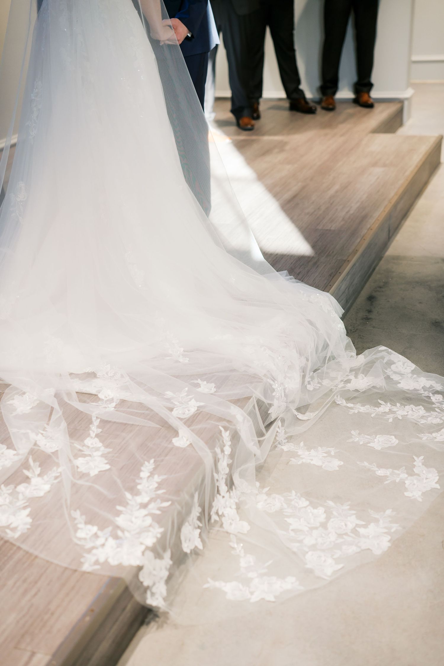 Close-up of intricate lace details on a flowing white wedding dress train.